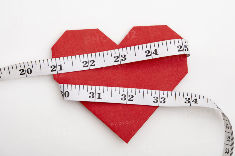 Measuring tape wrapped around red origami heart on white background
New York City, New York State, USA