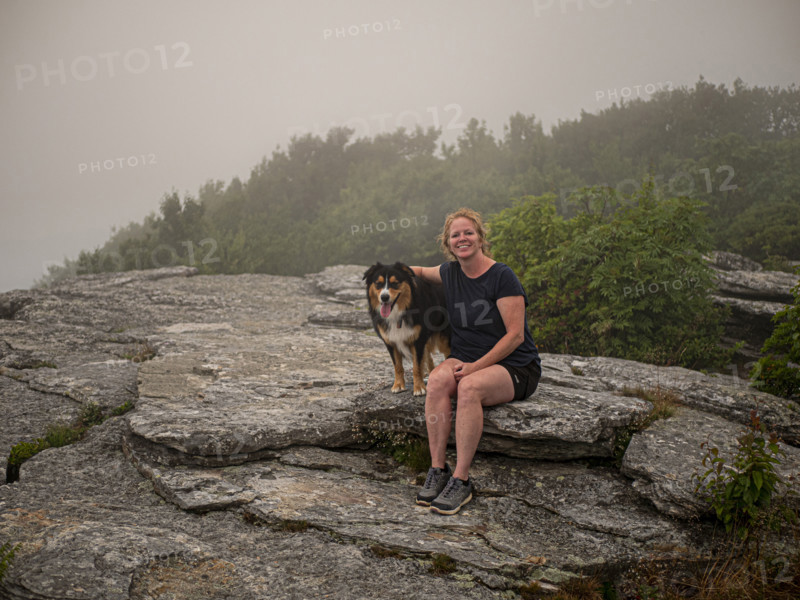 Portrait of smiling woman with Black Tri Australian Shepard sitting on rocks
Blacksburg, Virginia, USA