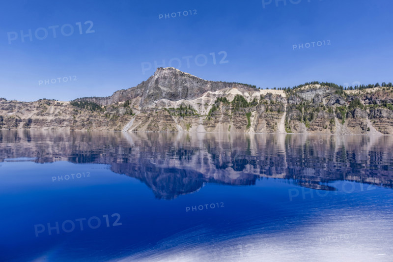 USA, Oregon, Cliffs reflected in calm surface of Crater lake