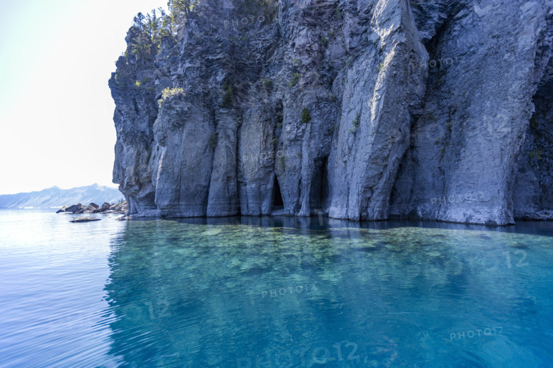 USA, Oregon, Cliff with caves by calm Crater lake