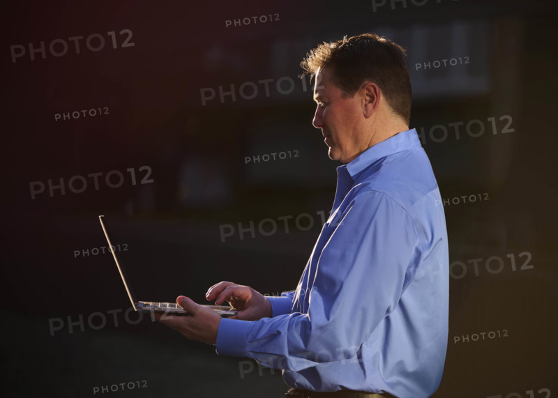 Man working on laptop and talking on phone outdoors