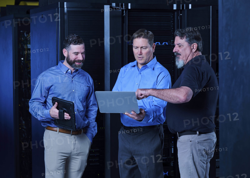 Workers looking at laptop in data center