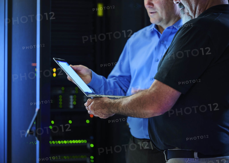 Workers looking at laptop in data center