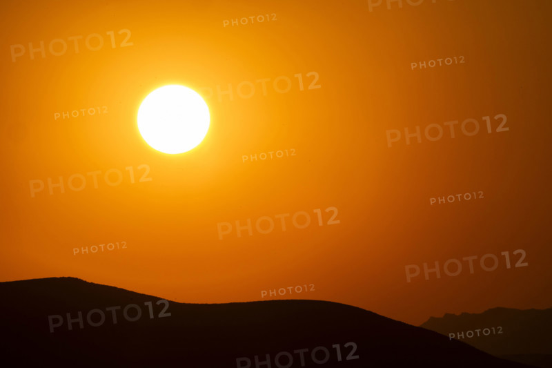 USA, Idaho, Bellevue, Setting sun over hills against orange sky