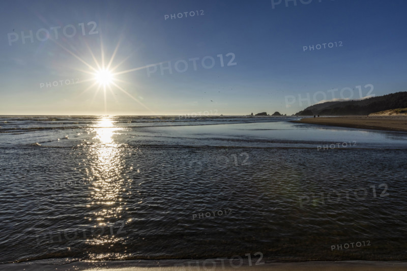 USA, Oregon, Sun setting over ocean and empty Cannon Beach