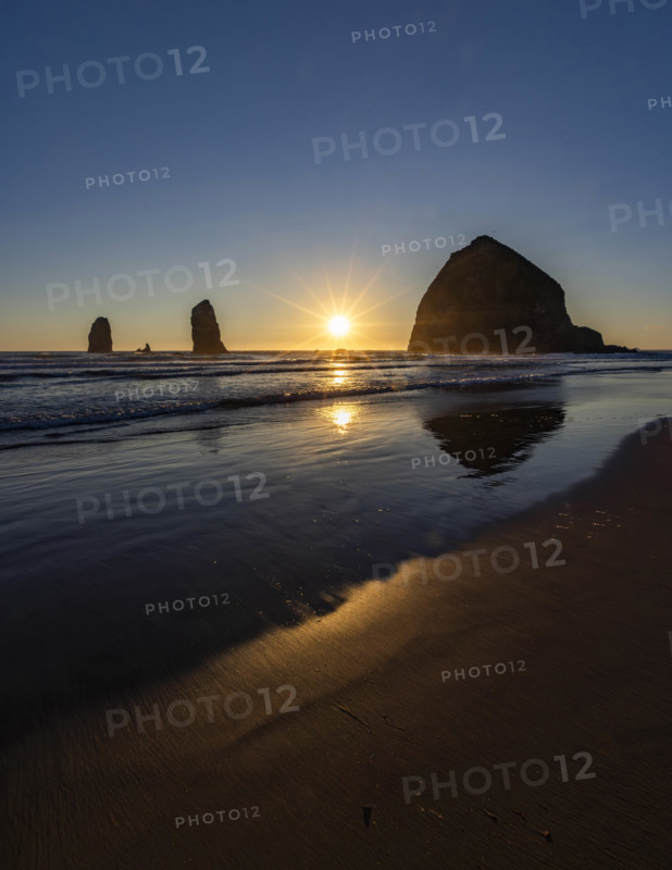 USA, Oregon, Sun setting behind haystack rock on Cannon Beach