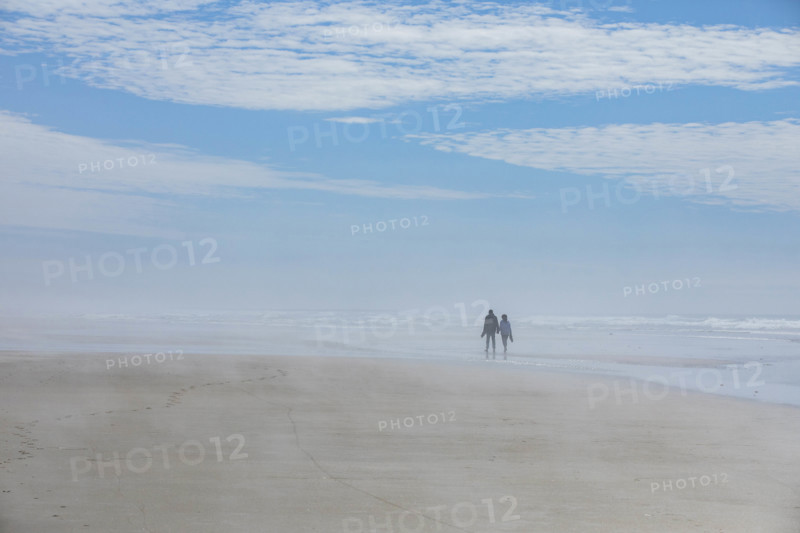 USA, Oregon, Newport, Rear view of couple walking on empty beach