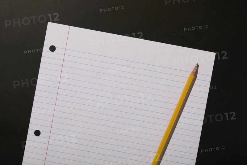 Lined paper and pencil on black background