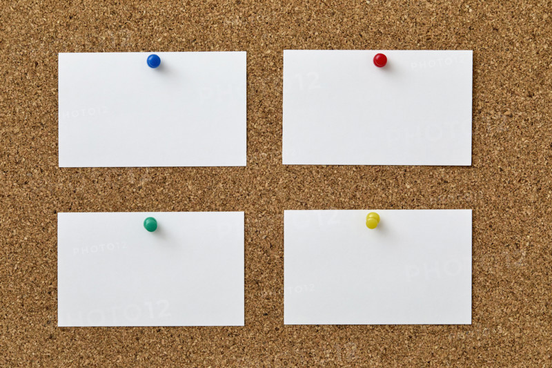 Blank pieces of paper attached to cork board with colorful push pins