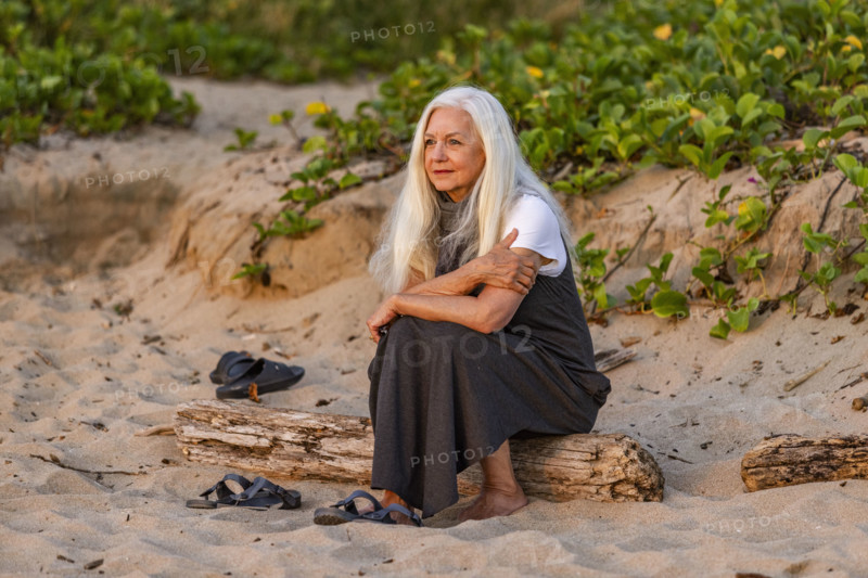 Senior woman sitting on beach at sunset