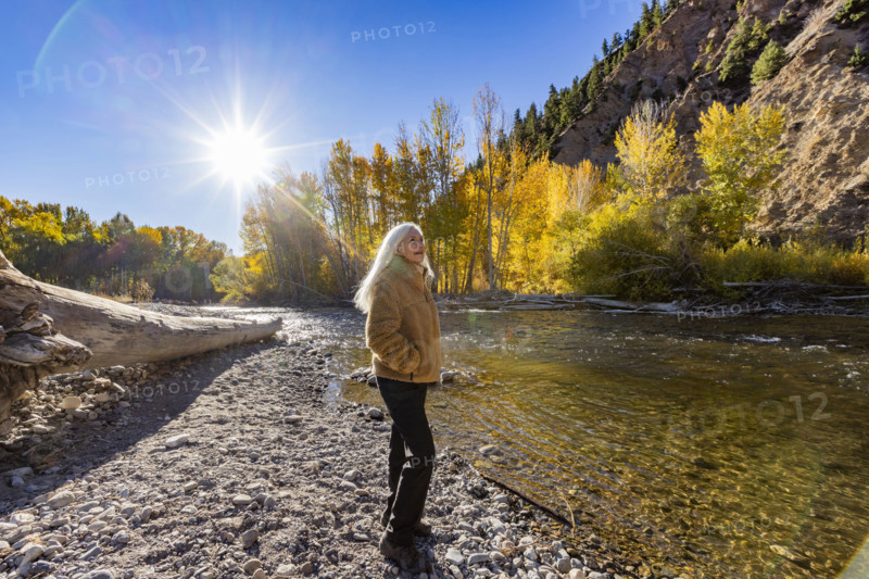 USA, Idaho, Hailey, Senior blonde woman at river in autumn