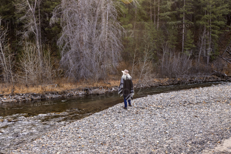 USA, Idaho, Sun Valley, Rear view of woman in wool poncho on riverbank