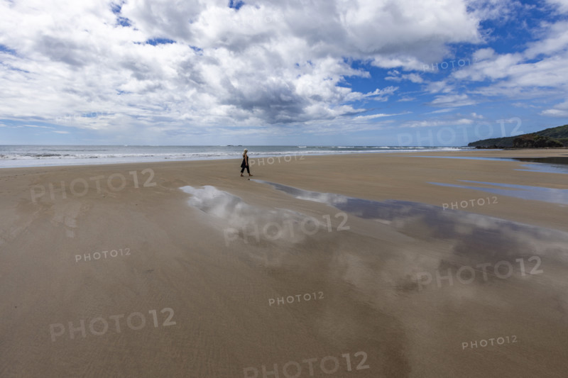 Costa Rica, Guanacaste, Playa Grande, Woman walking on empty beach at low tide
