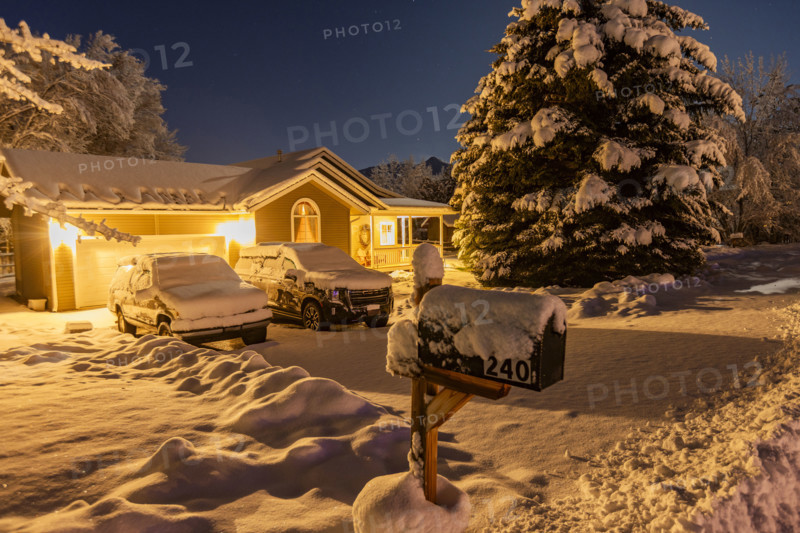 USA, Idaho, Bellevue, Illuminated suburban house and cars covered with snow at night