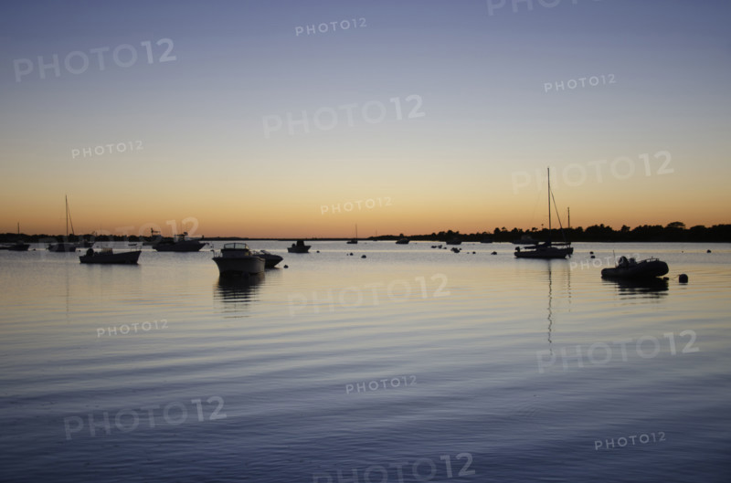 USA, Massachusetts, Nantucket, Boats on calm Polpis Harbor at sunset
