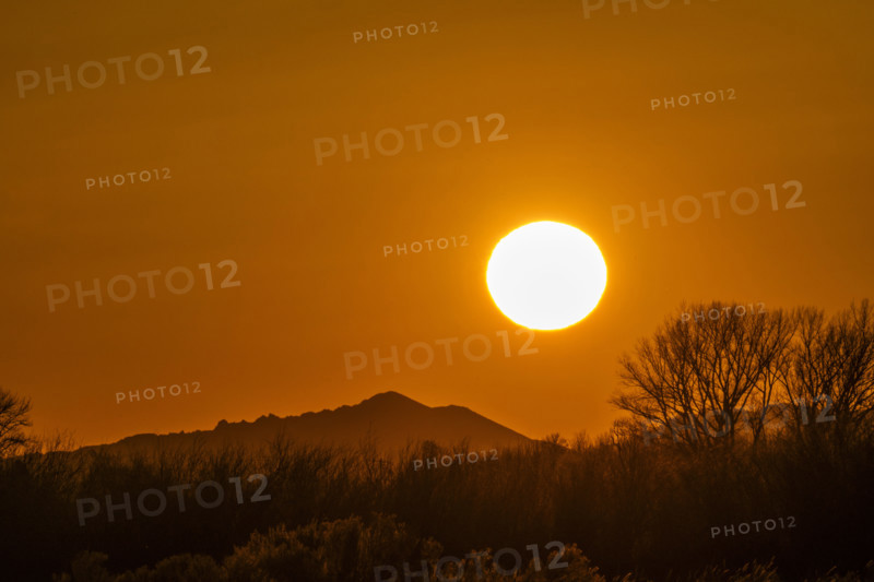 Sun setting above hills against orange sky. Bellevue, Idaho, USA.