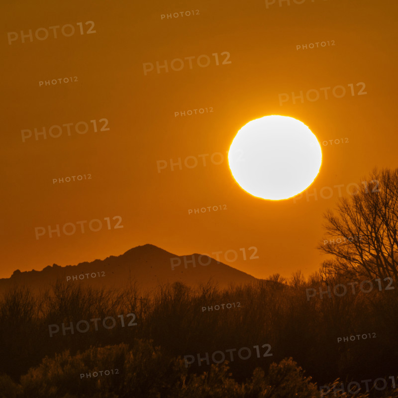 Sun setting above hills against orange sky. Bellevue, Idaho, USA.