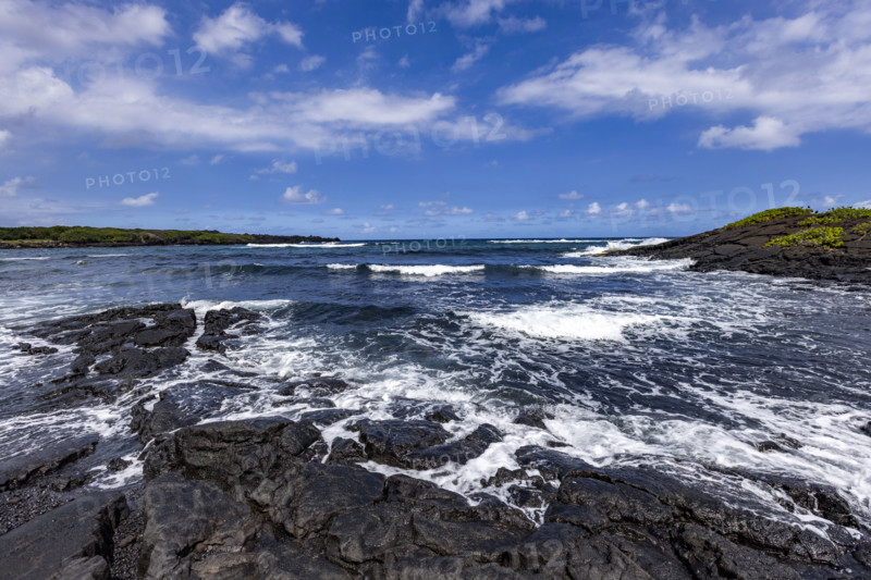 Motion blurred ocean waves washing coastal rocks. Kona, Hawaii, USA.