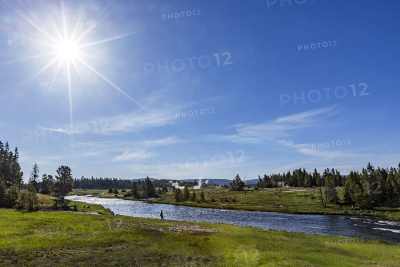 Sun on blue sky over Firehole River . , Wyoming, USA.