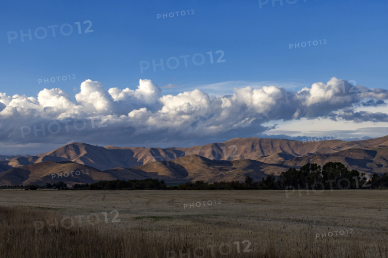 White puffy clouds over mountains and field. Bellevue, Idaho, USA.