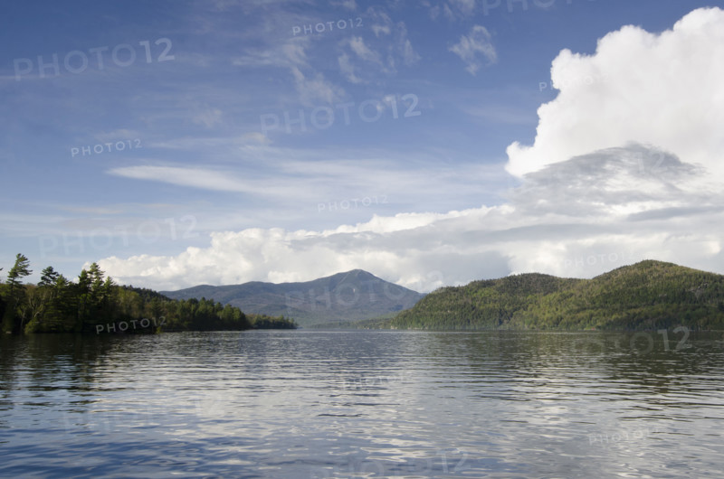 Puffy clouds over calm lake Placid . Lake Placid, New York State, USA.