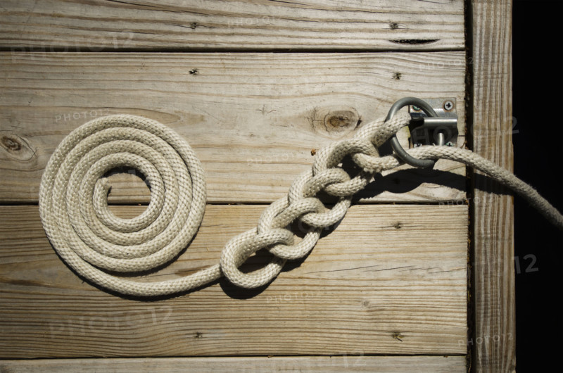 Boat rope tied and coiled on boat dock. Lake Placid, New York State, USA.