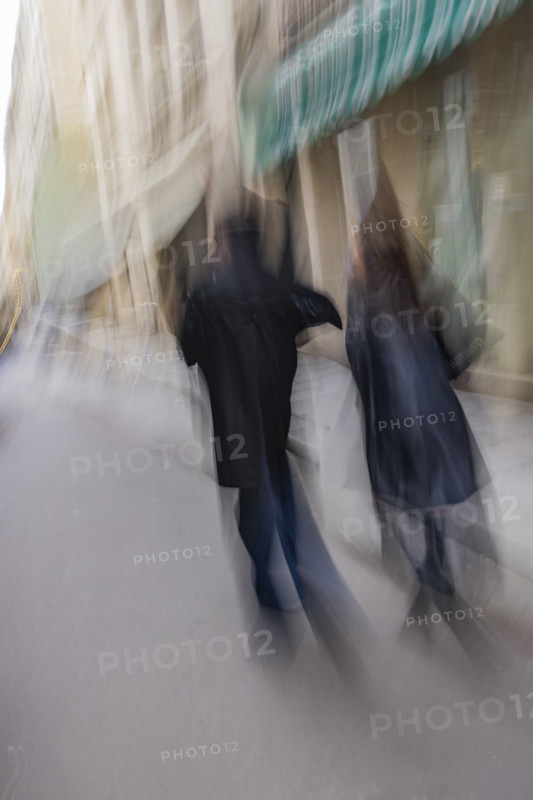 Rear view of couple walking down street, blurred motion. Paris, Ile de France, France.