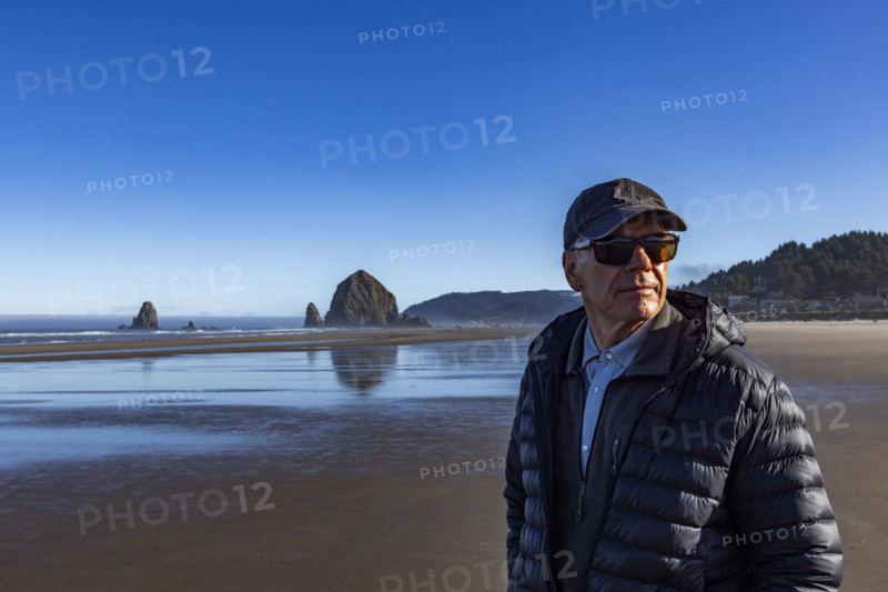 Portrait of senior man on beach with Haystack Rock in background. , Oregon, USA.