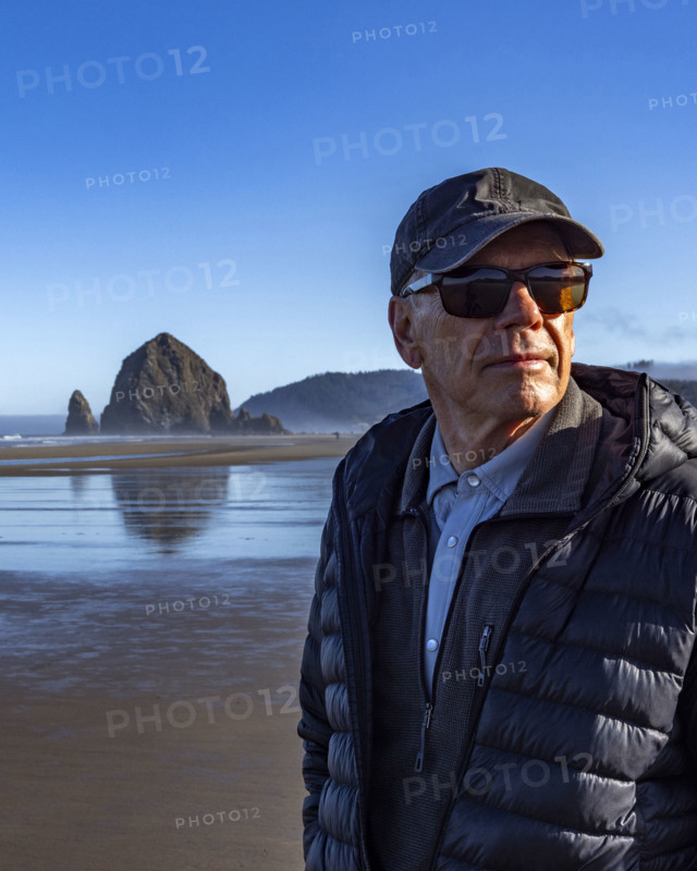Portrait of senior man on beach with Haystack Rock in background. , Oregon, USA.