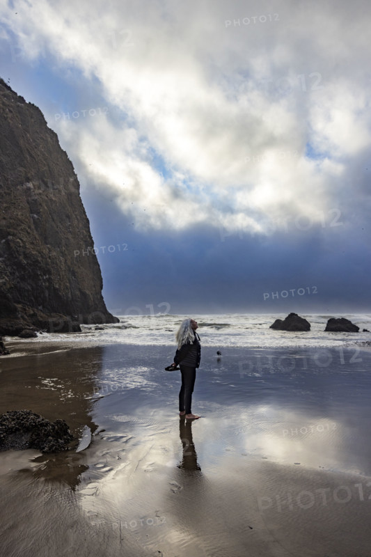 Senior blonde woman next to Haystock Rock. , Oregon, USA.