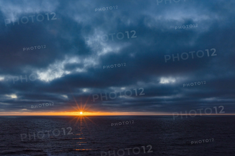 Dark clouds and sun stetting above ocean. La Jolla, California, USA.