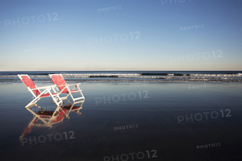Two beach chairs reflected in wet sand. York, Maine, USA.