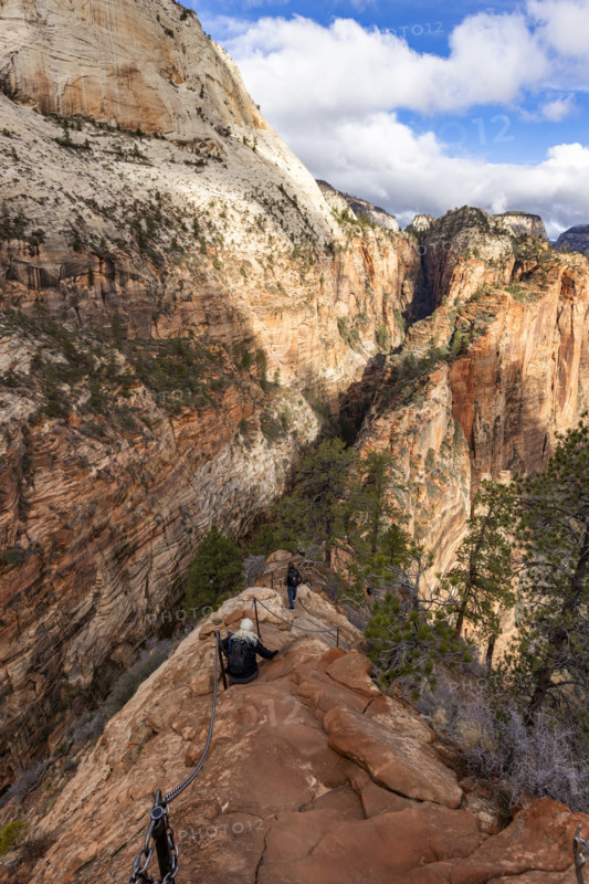Hikers descending Angels Landing Trail holding chains. , Utah, USA.