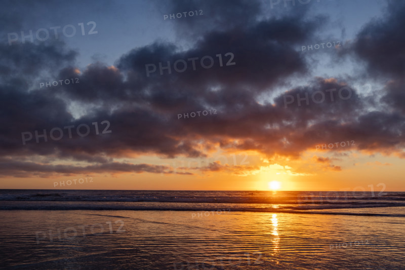 Sun setting over calm ocean. Oceanside, California, USA.