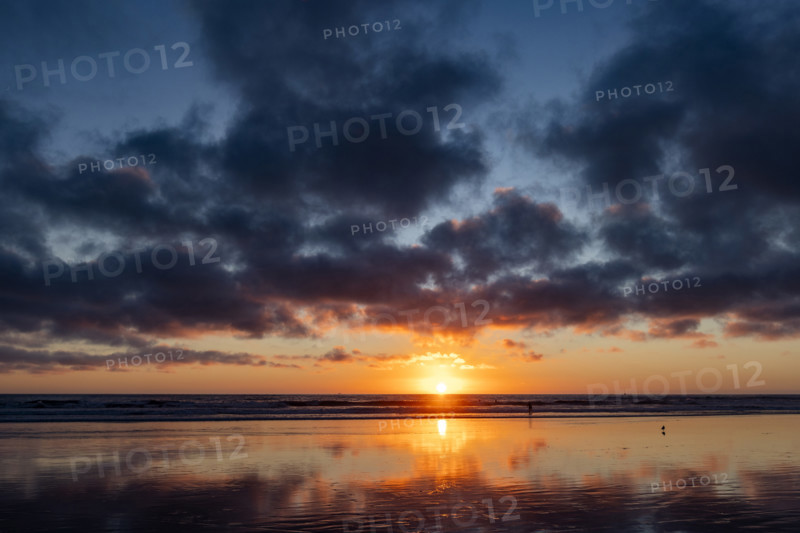 Sun setting over calm ocean. Oceanside, California, USA.