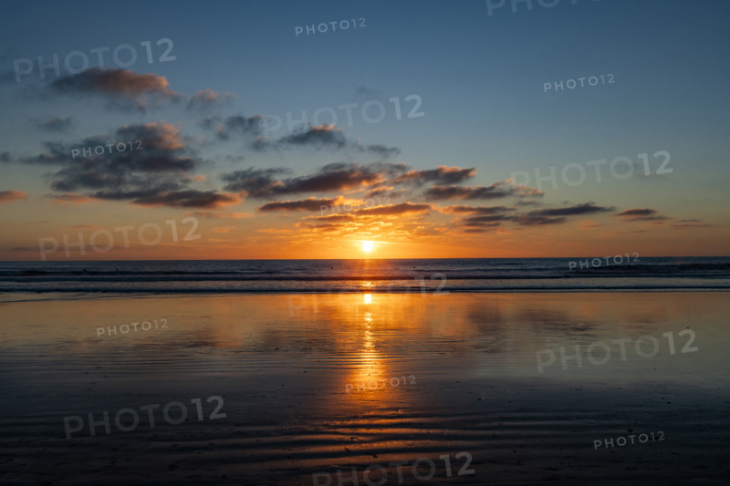 Sun setting over calm ocean. Oceanside, California, USA.