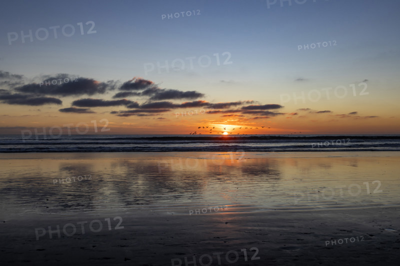 Sun setting over calm ocean. Oceanside, California, USA.