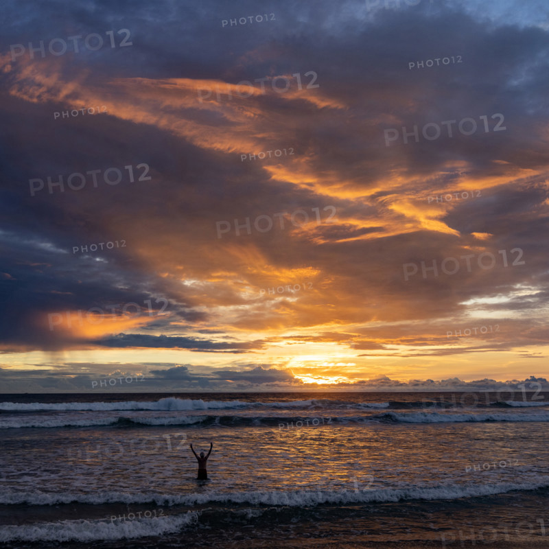 Silhouette of person with arms raise in sea at sunset. , Guanacaste, Costa Rica.