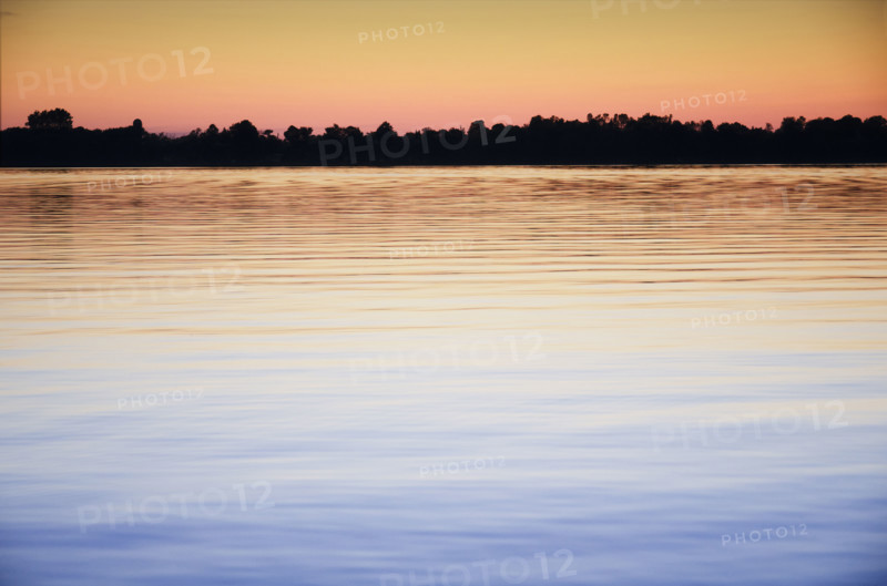 Calm Black Lake reflecting sky at sunset. Hammond, New York State, USA.