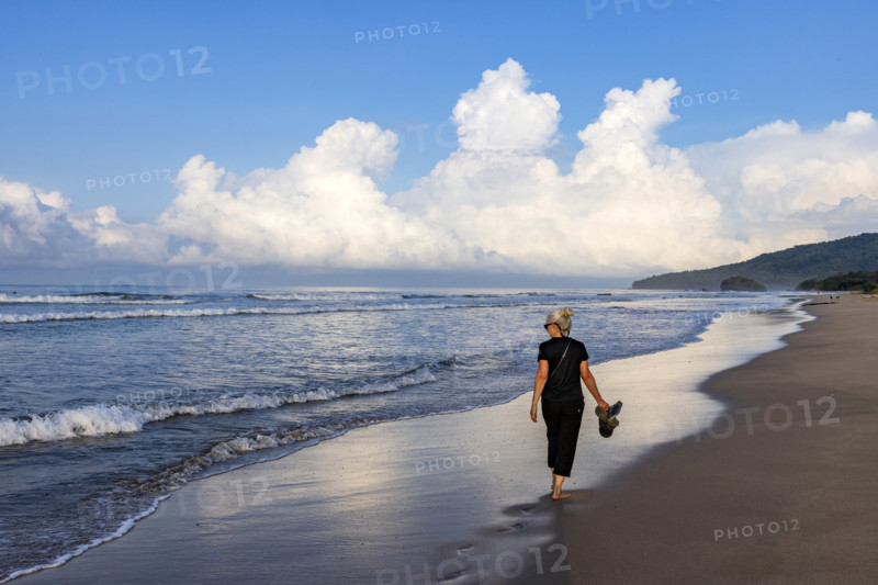 Rear view of woman walking on beach at dawn, Playa Grande, Guanacaste, Costa Rica.