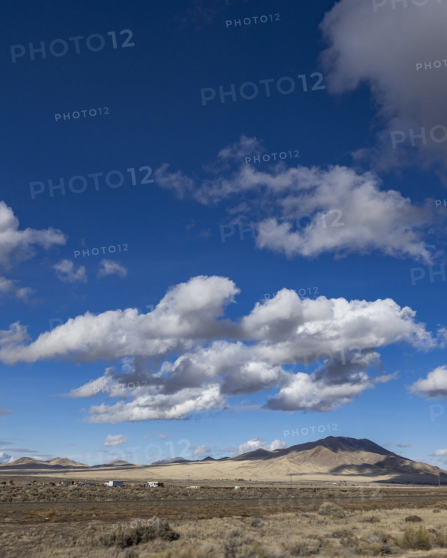 White puffy clouds above Interstate 80 crossing barren landscape, Winnemucca, Nevada, USA.