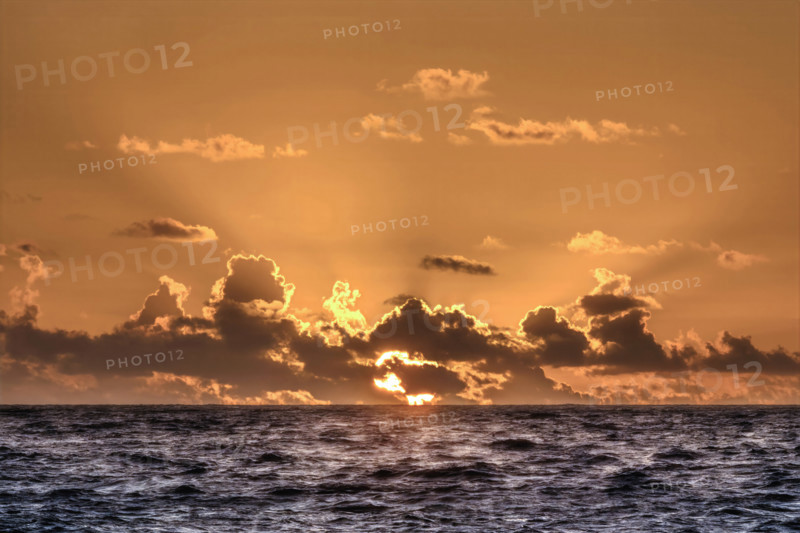 Sun rising through clouds over Atlantic Ocean, Boca Raton, Florida, USA.
