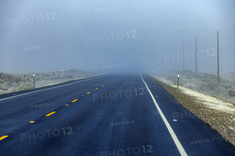 Two lane highway leading into fog bank