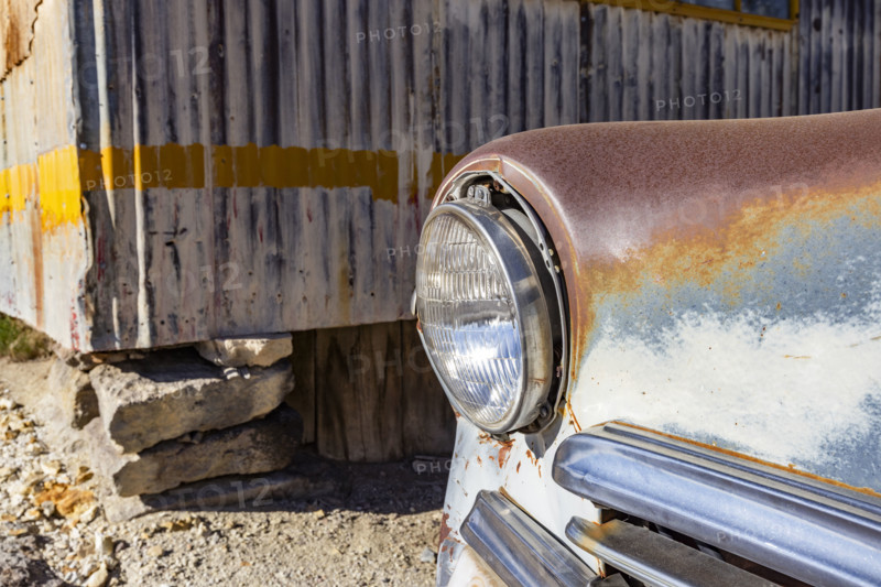 Close-up of abandoned car next to sheet metal building