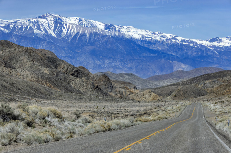 Empty two-lane highway through desert to mountains