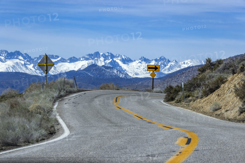 Empty two-lane highway through desert to mountains