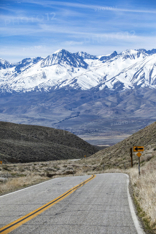 Empty two-lane highway through desert to mountains