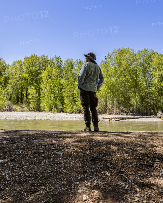 Rear view of man standing near river in forest