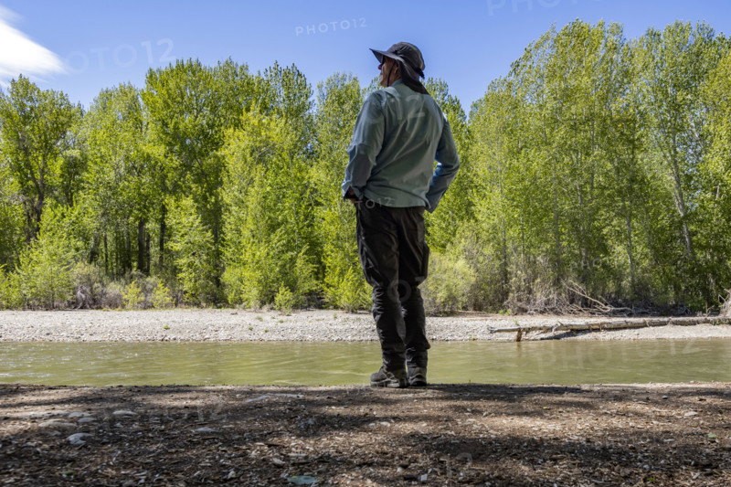 Rear view of man standing near river in forest