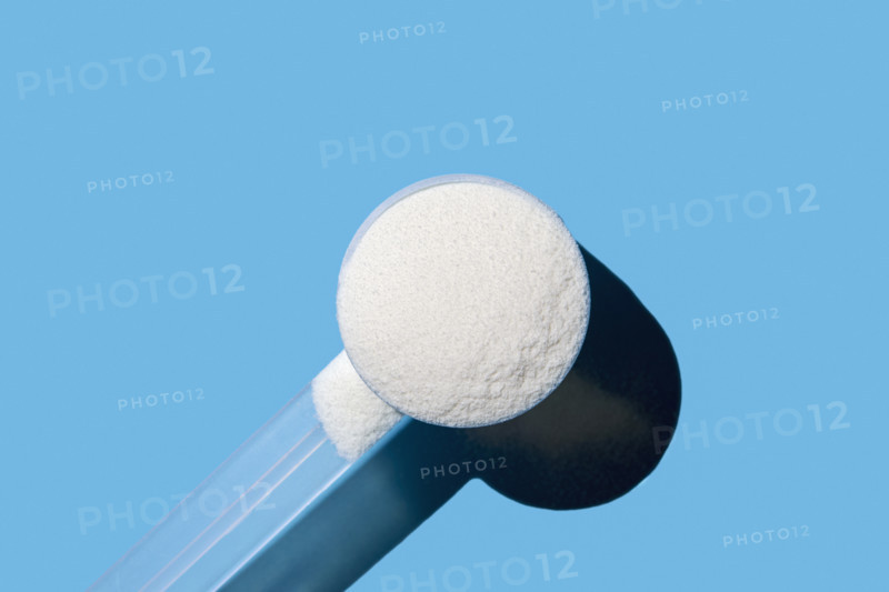 Scoop of collagen powder on blue background